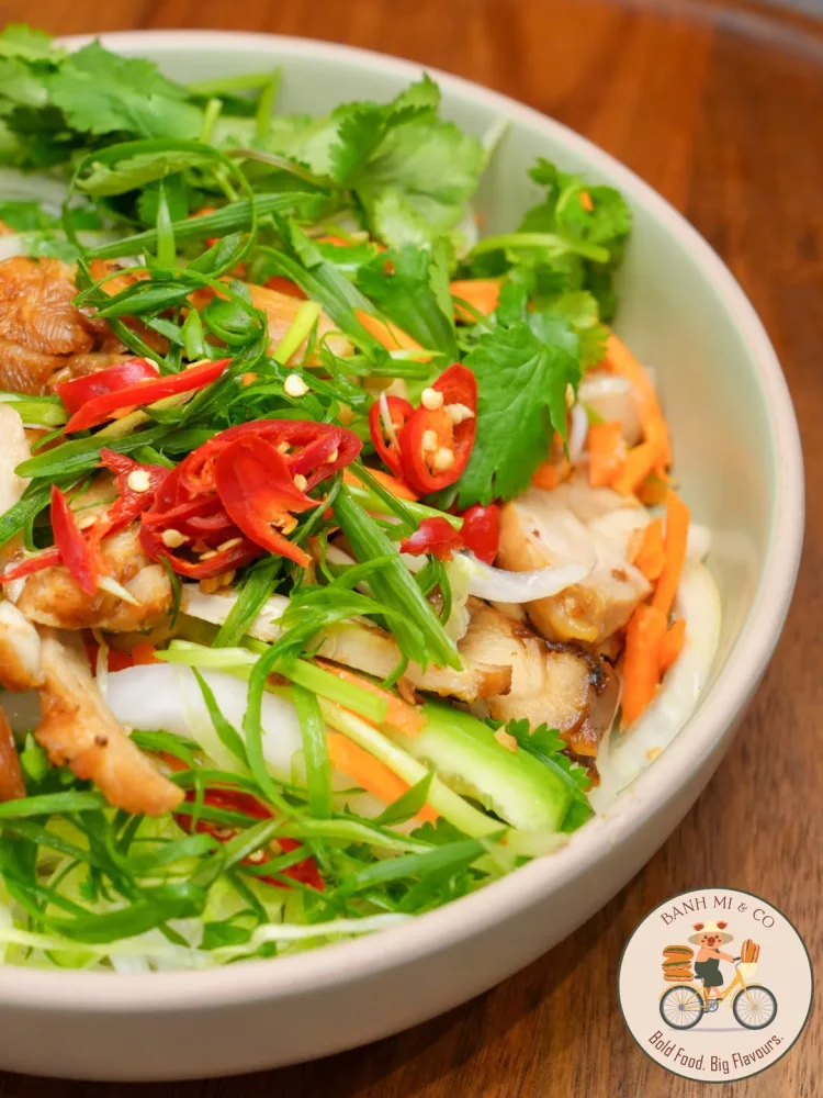 Chicken salad bowl topped with fresh herbs and sliced chilli