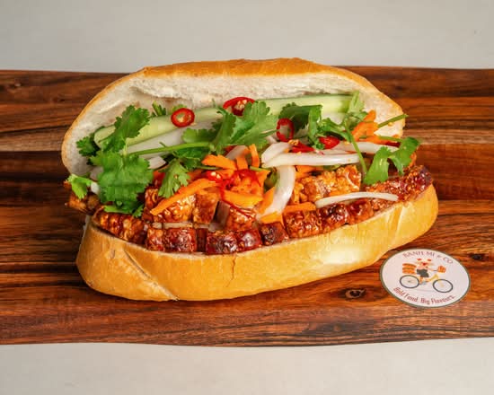 Crackling pork bánh mì with fresh vegetables on a wooden board